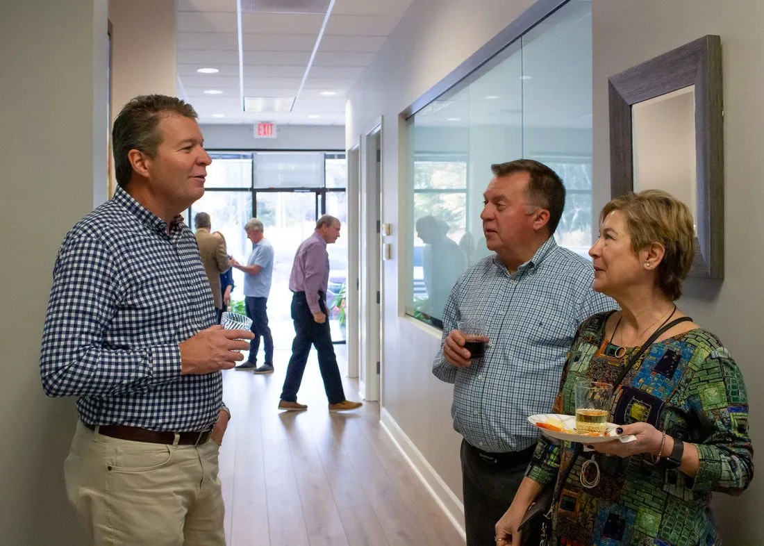 A group of people are standing in a hallway talking to each other.